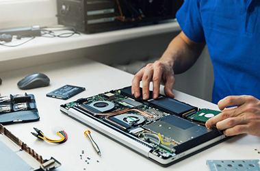 computer repairman installing new hard disk drive in laptop